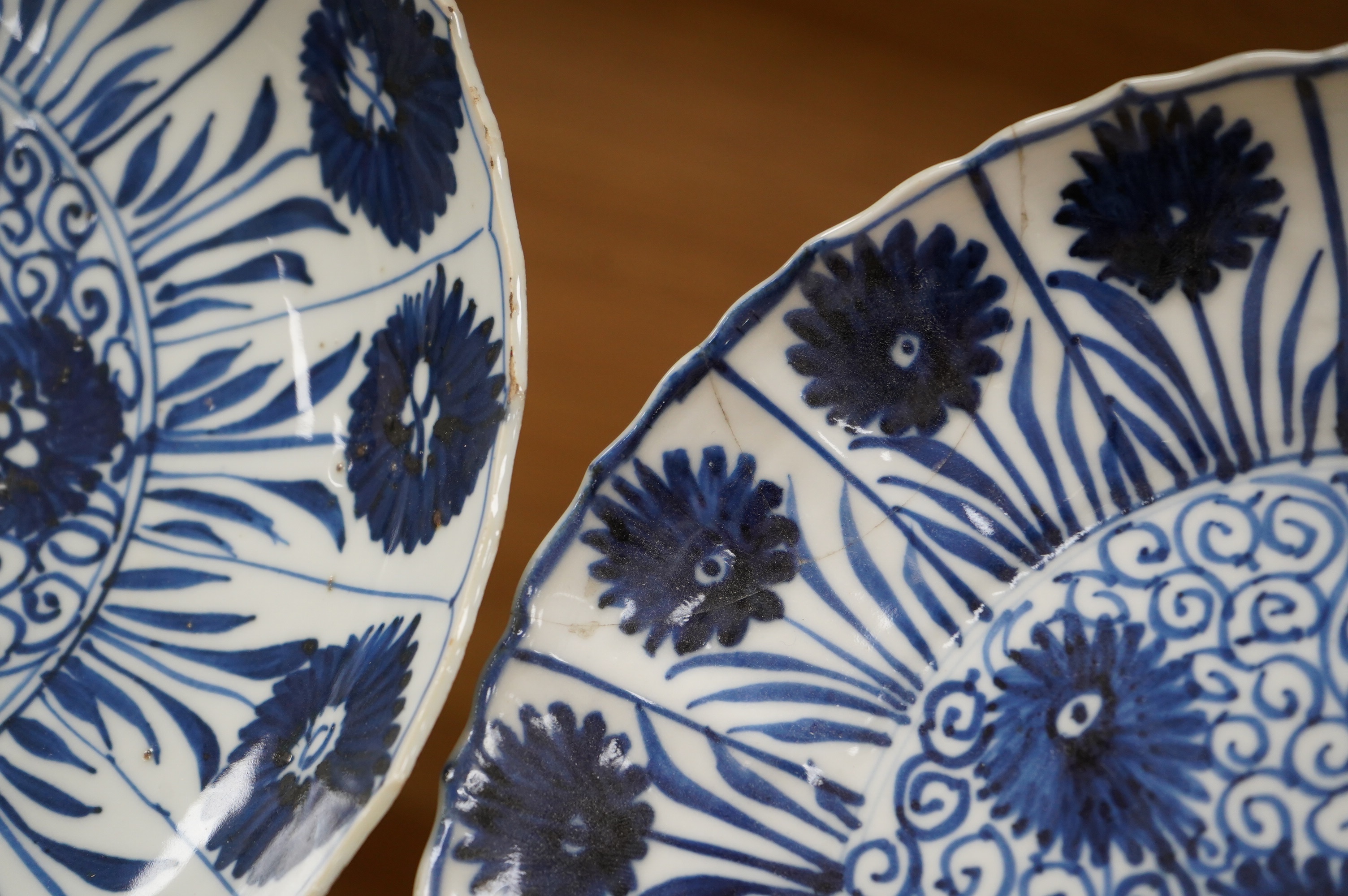 Two Chinese blue and white ‘astor’ plates, Kangxi period, with hardwood stands, largest 22cm diameter. Condition - poor to fair